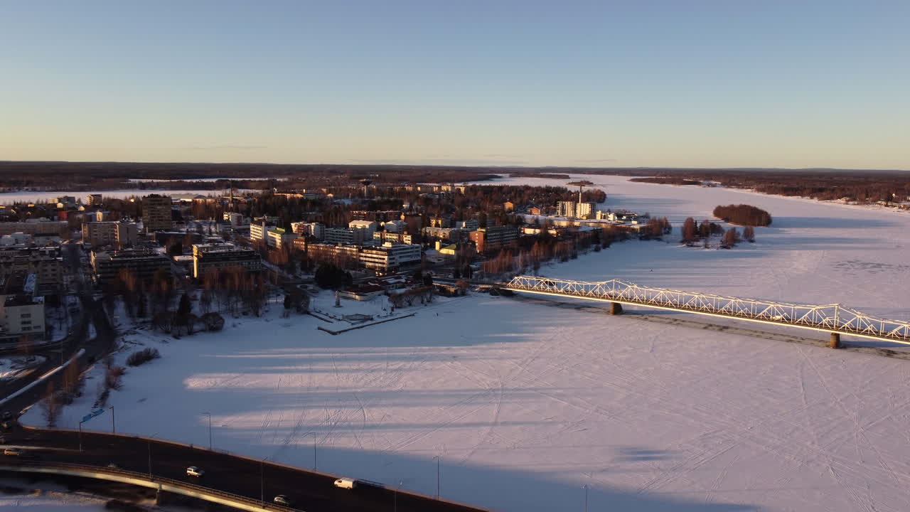 Aerial flying backwards from buildings on banks of frozen Torne River in Tornio, Finland
