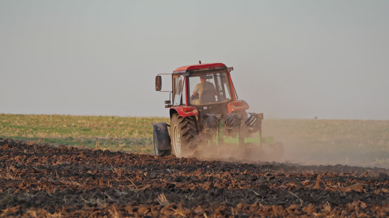 Back view of a tractor plowing the soil. Agricultural machinery preparing land for further works on the field. Process of cultivation the ground.