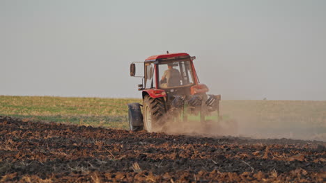 back view of a tractor plowing the soil. agricultural machinery preparing land for further works on the field. process of cultivation the ground.