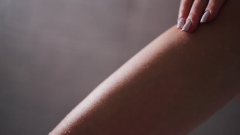 la mujer acaricia la pierna suave en el baño de primer plano. la dama disfruta de la piel suave y hidratada de la pierna sobre un fondo claro. procedimientos de spa para el cuidado del cuerpo y belleza