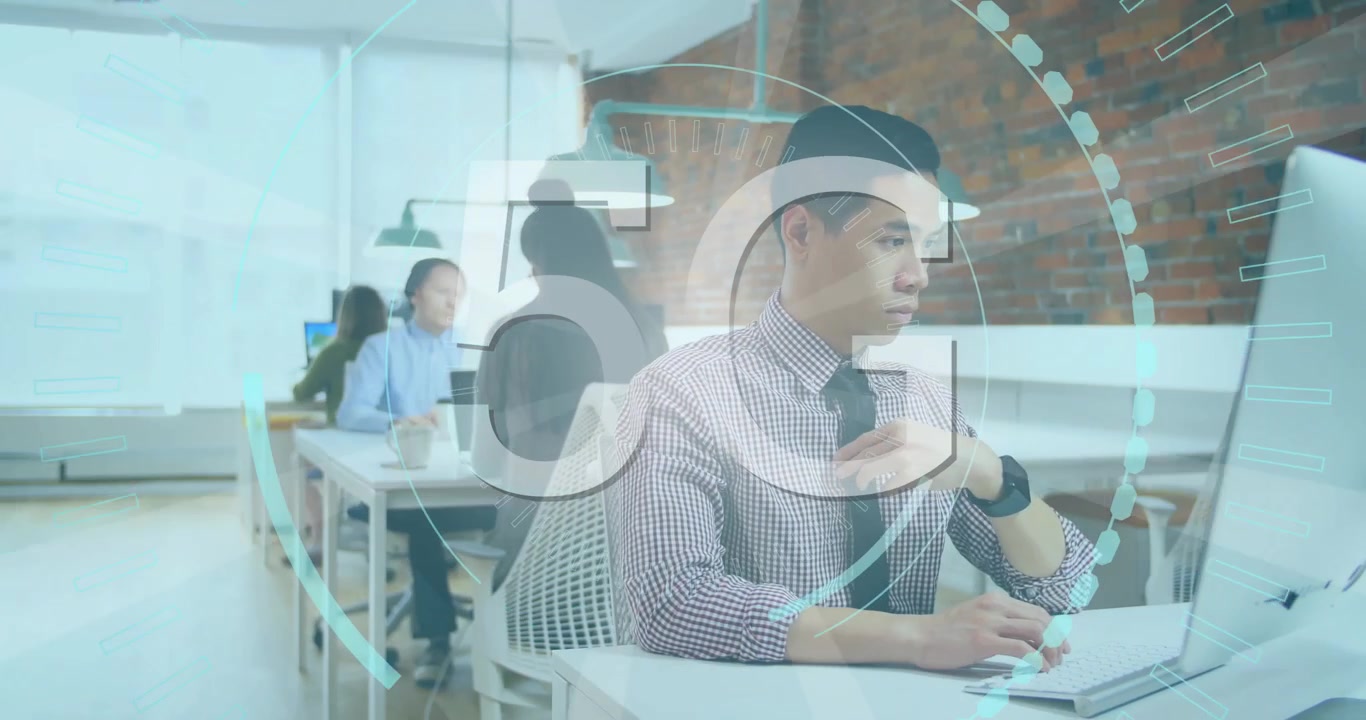 ローディングサークル内で5Gのテキストがアニメーション表示され、アジア人男性がコンピューターで作業しながら時計を見ている。