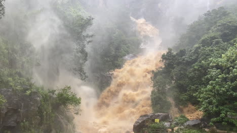handheld shot of ravana falls at high discharge after heavy rainfall flooding muddy water in ella sri lanka