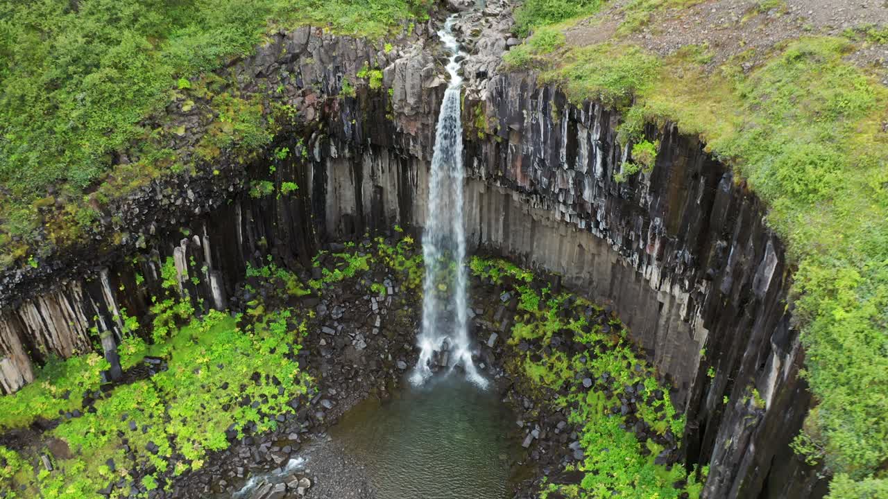 la popular cascada svartifoss y sus columnas de basalto, skaftafell, parque nacional vatnajökull, islandia - toma aérea de drones