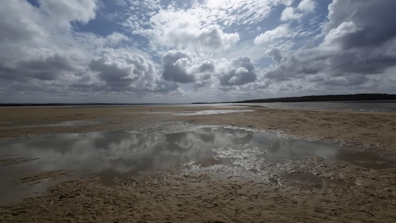 Dolly in landscape shot of a tropical wet sand bar during low tide in the Guara&iacute;ras Lagoon of Tibau do Sul, Brazil in Rio Grande do Norte during a sunny summer cloudy day near Pipa