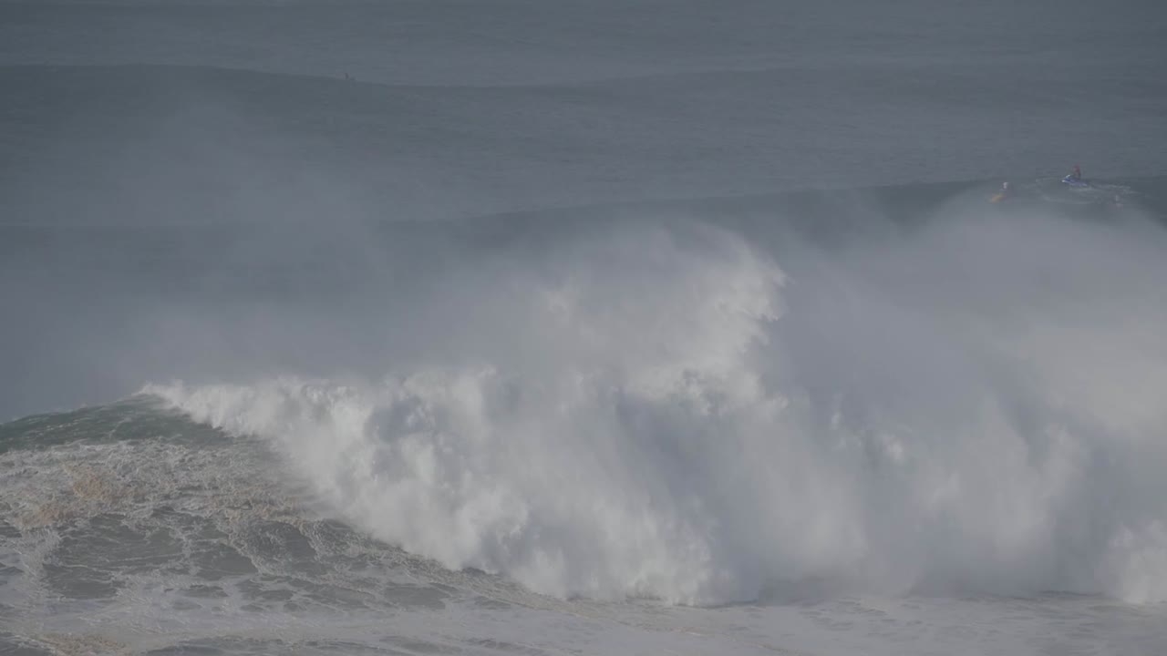 Rough ocean wave crashing at Praia de Nazaré, Portugal, with a misty atmosphere
