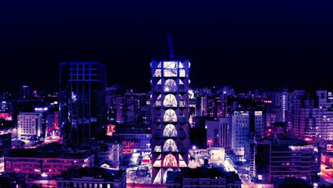 night cityscape view of a modern city with a tall building under construction.