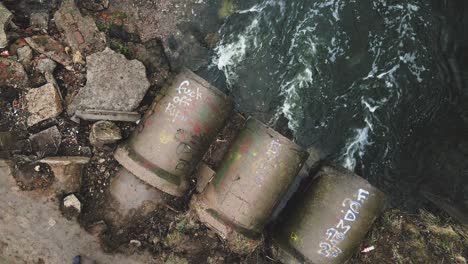 flying over concrete sewers. streams of water flow through concrete pipes. polluted body of water in the park. camera down