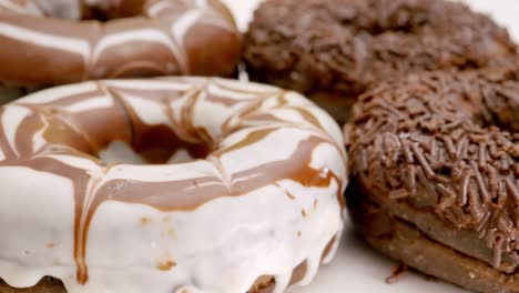 close up of chocolate donuts on a rotating wooden plate.