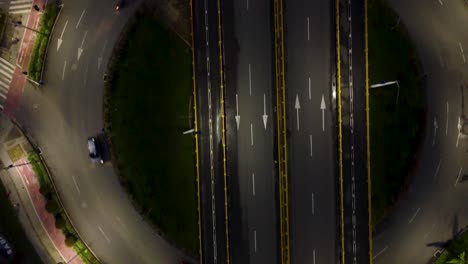 perspectiva de una carretera muy transitada por la noche y una rotonda debajo de una calle elevada