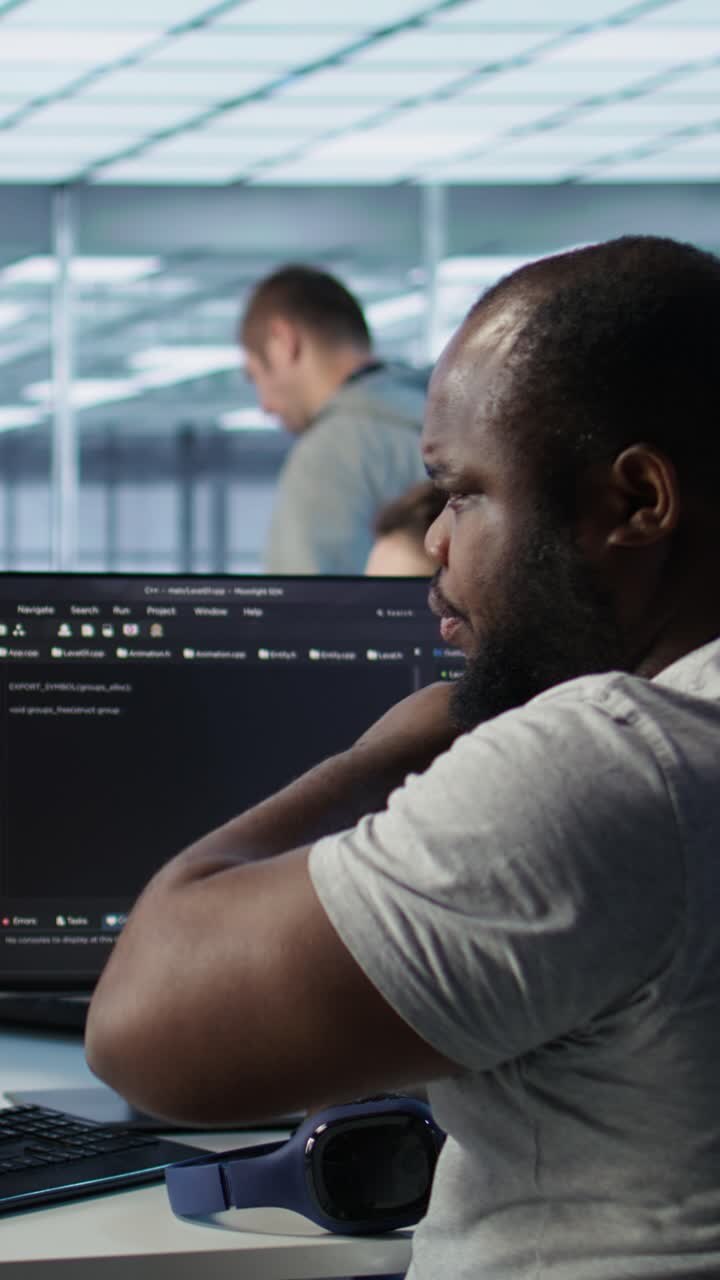 Afroamerikansk mand koder ved computeren på et moderne kontor