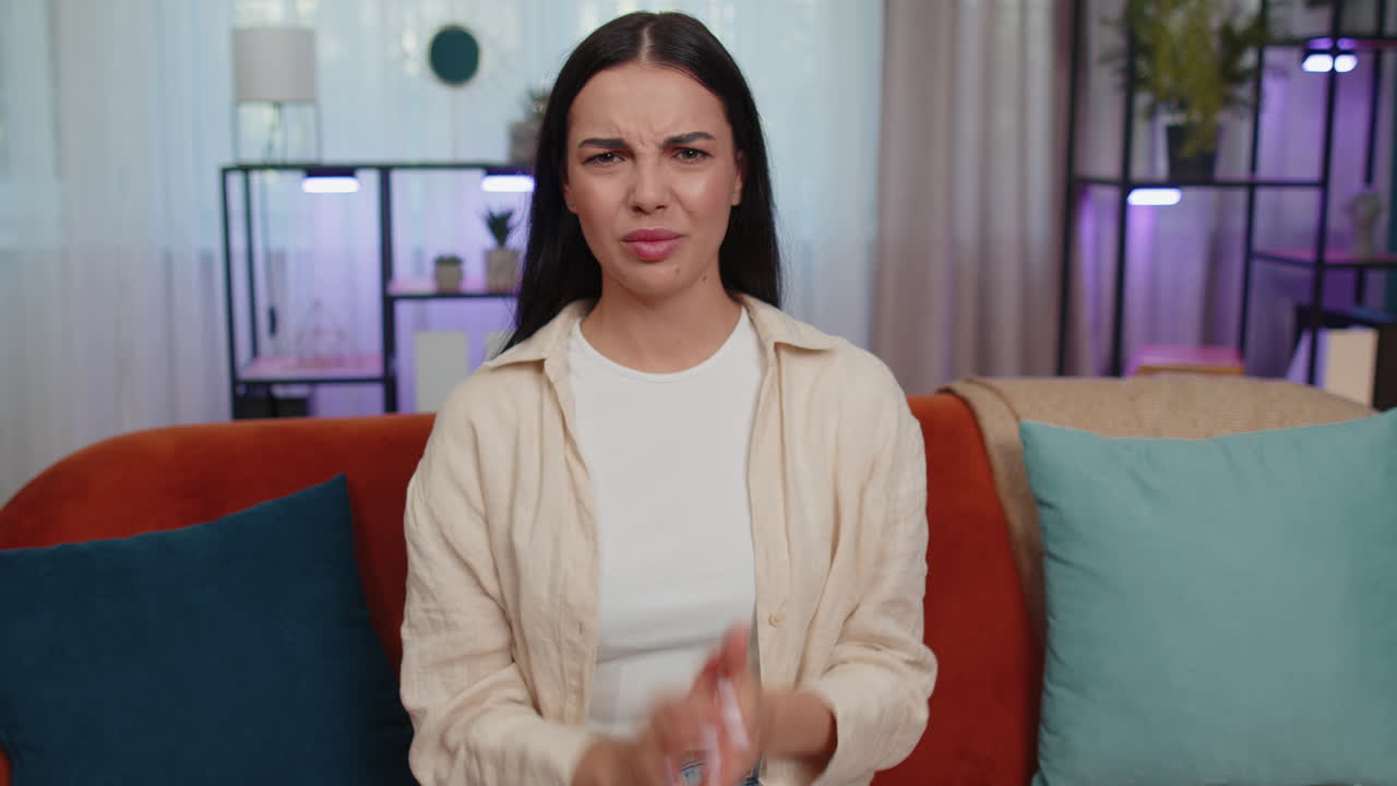 Upset young woman showing thumbs down, dislike bad work, disapproval, dissatisfied feedback at home