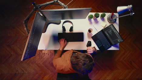 vista de arriba hacia abajo de ingeniero desarrollando código de pc, bebiendo café, escuchando música