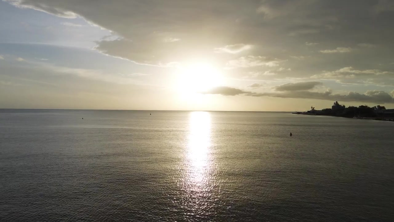 Smooth cinematic drone forward dolly over calm tropical ocean waters during sunset with
glowing reflections, soft clouds, and peaceful coastal atmosphere.