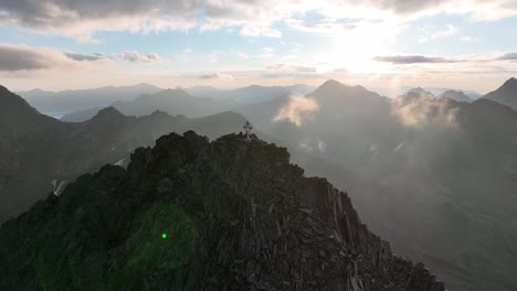 two people standing on a summit with stainless steel mountain cross in austria