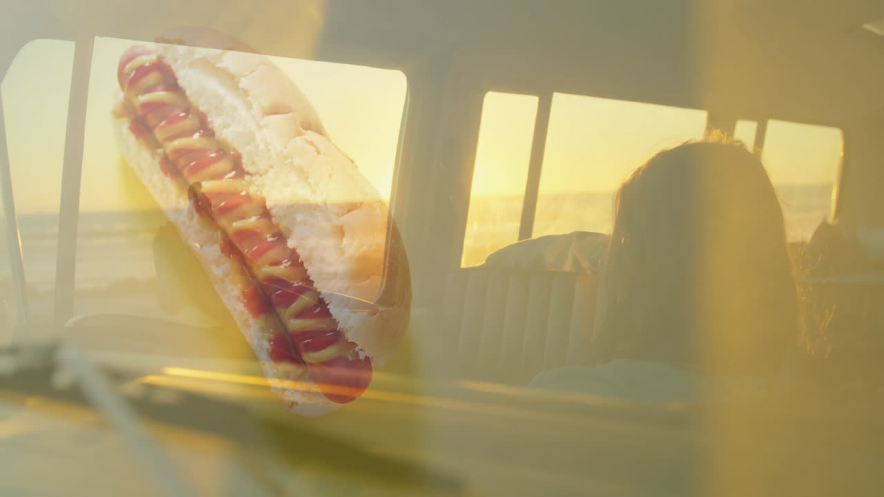 Hot dog with mustard and ketchup, sunset view through car window