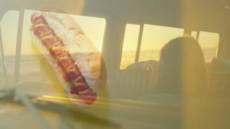 hot dog with mustard and ketchup, sunset view through car window