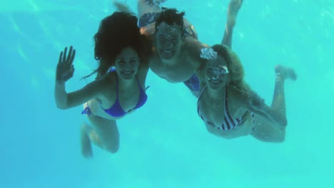 tres amigos buceando en la piscina y agitando