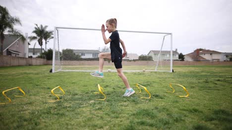 a young girl is warming up for practice by doing high kees over a set of speed hurdles