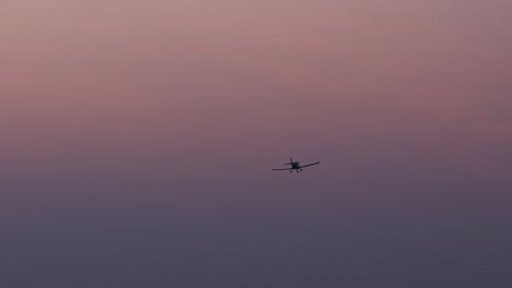 a light aircraft flying high into an exquisite pink purple sunset