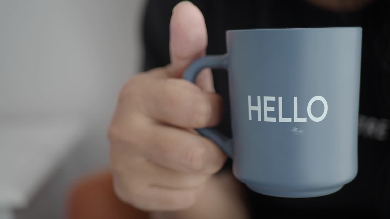 persona sosteniendo una taza con la palabra "hola"