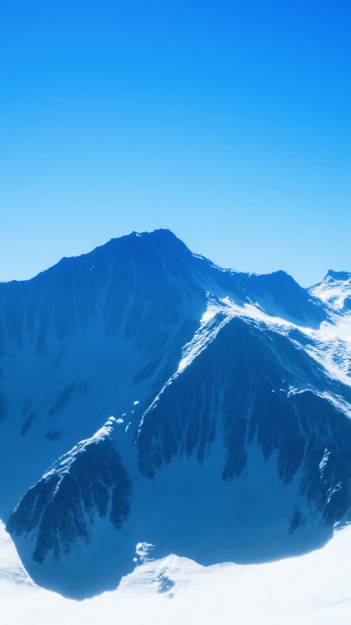 Snowy mountain peaks under clear blue sky in winter landscape view