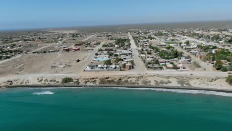 aerial view move away shot, scenic view of the town of san juanico, california sur, mexico, waves from the sea in the background