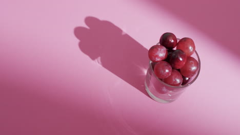 video de uvas rojas en vidrio con espacio de copia en fondo rosa