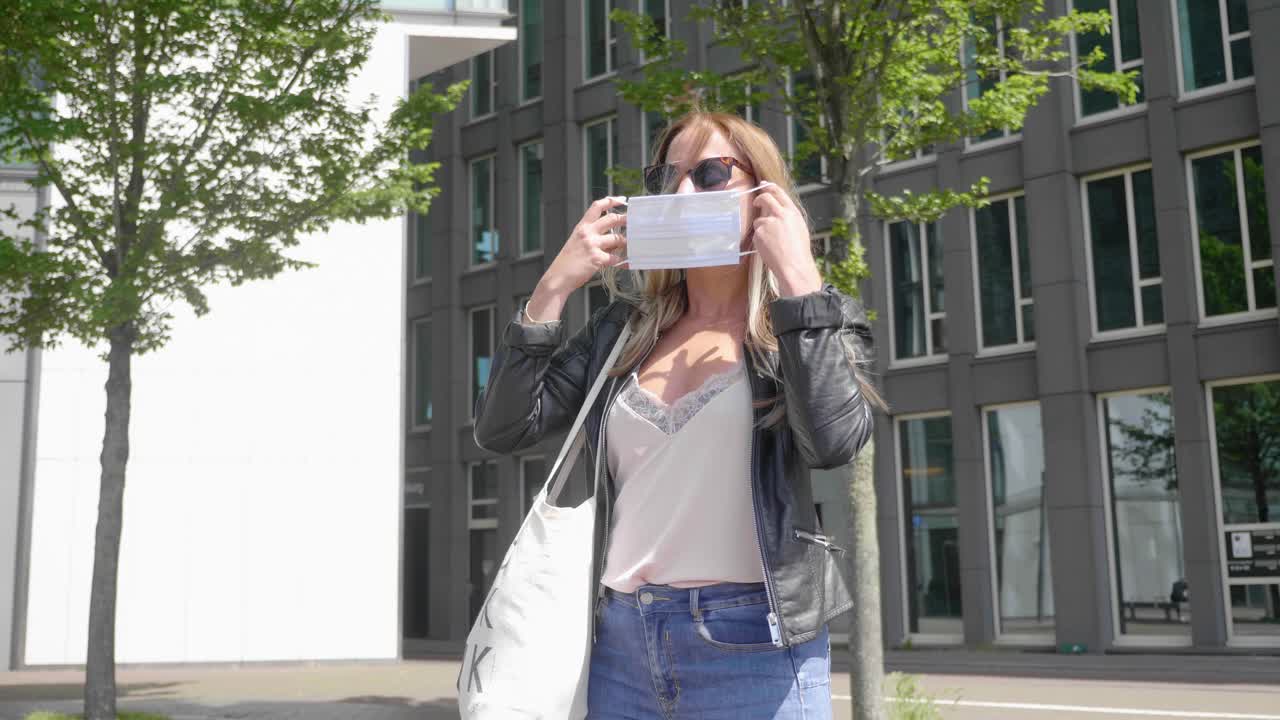 Pretty Blond Woman With Dark Sunglasses Put On Facemask In Amsterdam, Netherlands