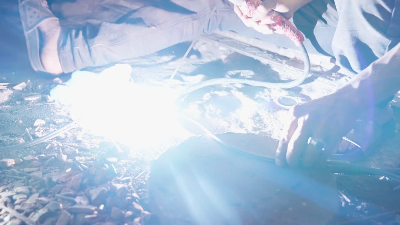 Worker manipulating electrical cables on a dirty concrete floor in a gritty indoor setting