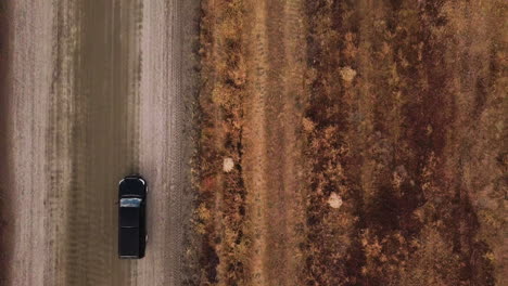 Suv-cruising-on-the-dry-landscape-road-of-California-aerial-shot