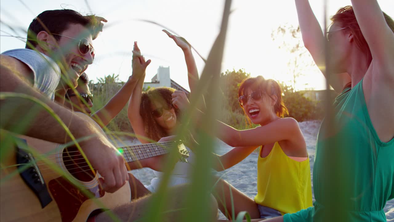 hombres y mujeres multiétnicos disfrutando de un picnic en la playa.