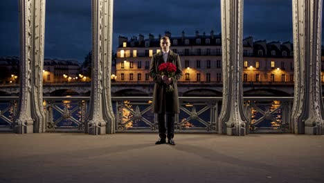 man with roses on a parisian bridge at night