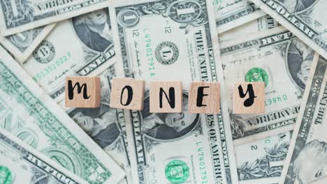 rotating word money from wooden letters, on dollars, concept