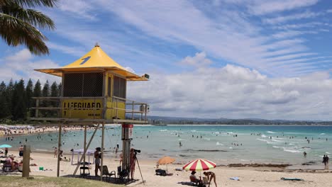 sunny beach scene with lifeguard tower and swimmers