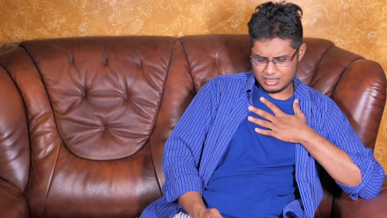 hombre sentado en el sofá toser