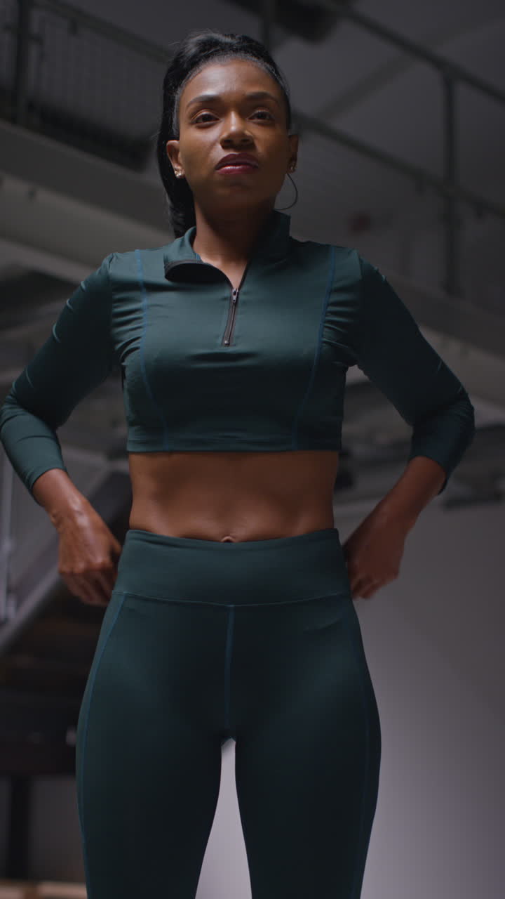 체육관에서 운동복을 입고 운동하는 여성 선수의 수직 비디오 스트레칭과 체육 행사에 대비하는 워밍업