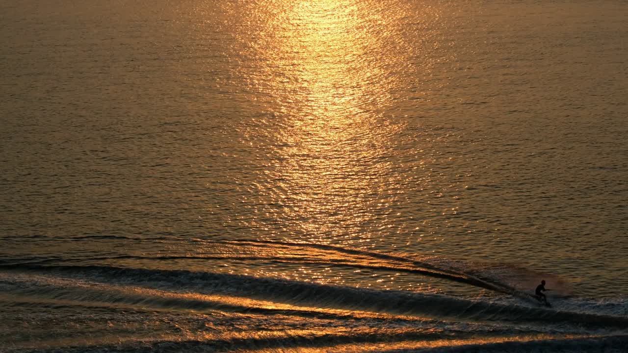 황금빛 해가 지는 바다 표면에서 물 스키를 타는 것