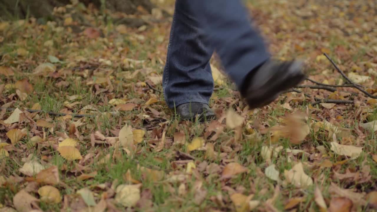 Feet kicking autumn leaves in rural scene