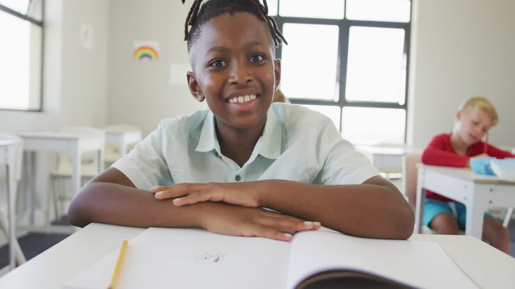 vidéo d'un garçon afro-américain heureux assis au bureau de l'école