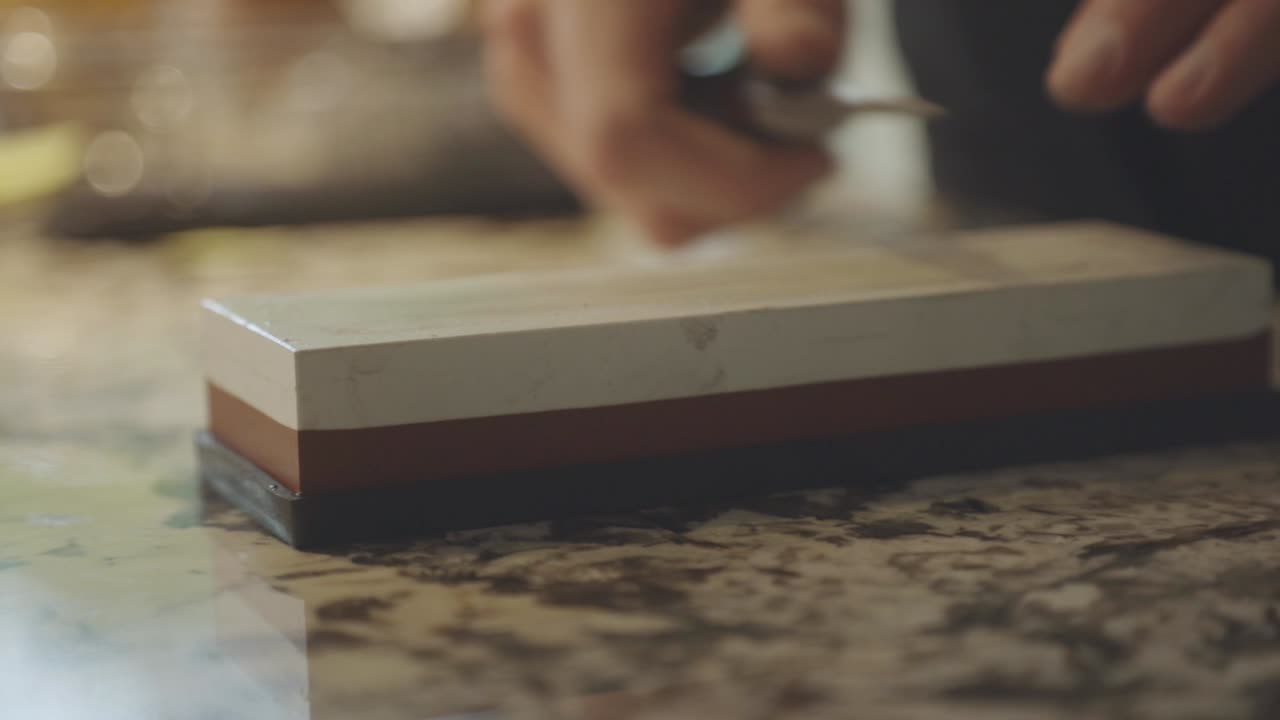 Person's Hand Sharpening Small Knife On Whetstone