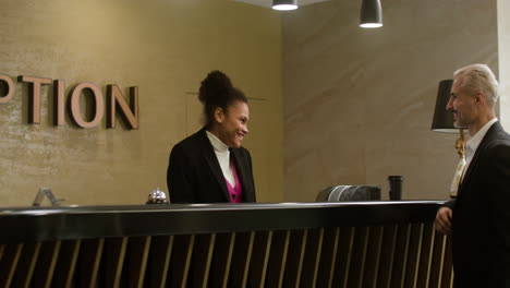 receptionist assisting a guest at the hotel reception desk