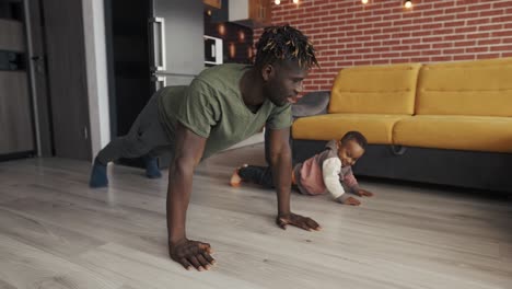 Father-and-positive-preschool-mixed-race-boy-doing-push-ups-exercise-in-domestic-room