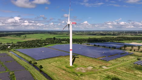 a wind turbine spins in the middle of a solar farm