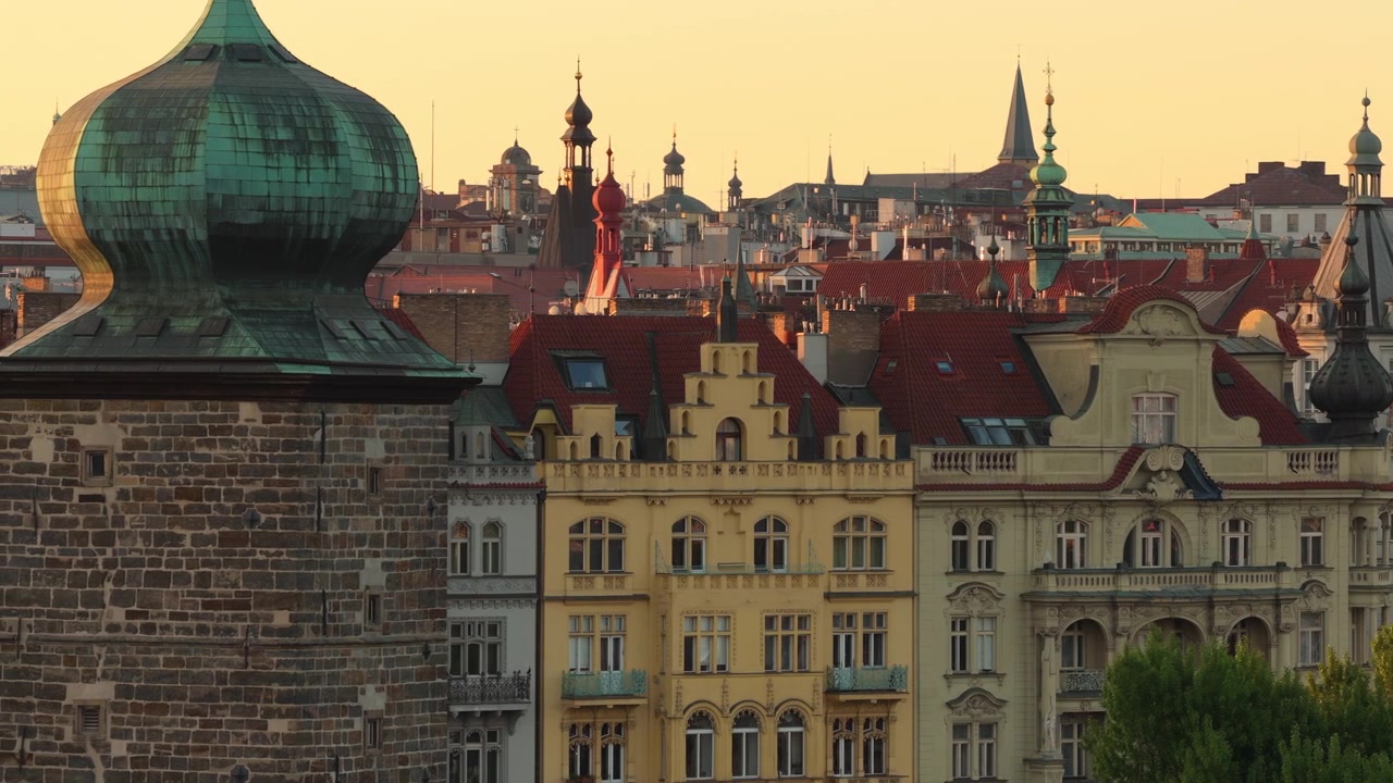 Vista aerea con drone dei tetti storici di Praga con dettagli di torri a cupola a cipolla in rame e guglie barocche alla calda luce dell'ora d'oro, Praga, Repubblica Ceca.