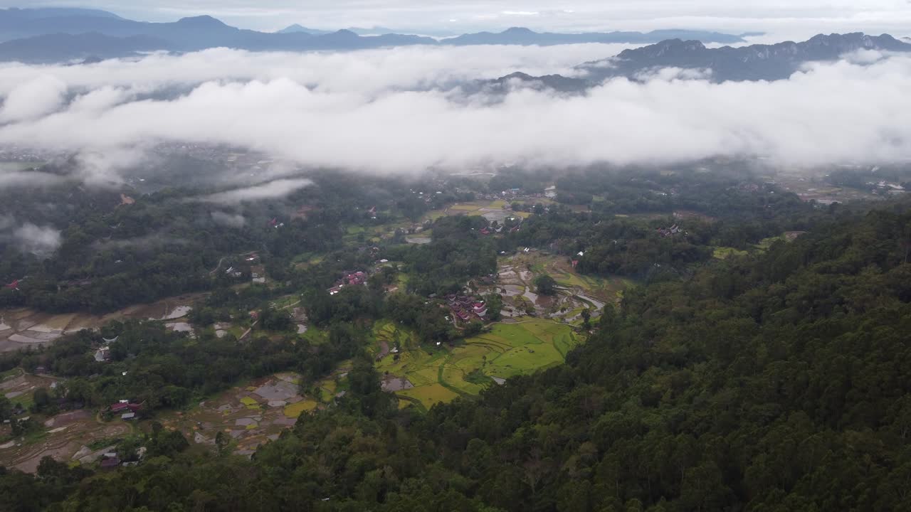 Aerial View of a Lush Valley with Rice Paddies and Villages Amidst Mountains and Clouds
