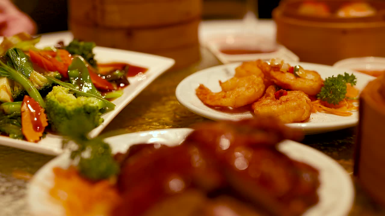 A vibrant display of dimsum and deep-fried shrimp in a warm, inviting restaurant setting with rich lighting