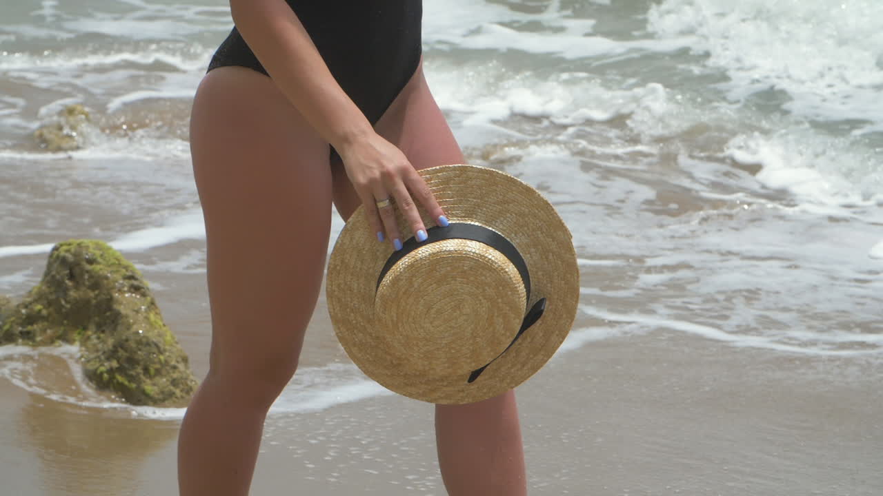 mujer en un traje de baño negro caminando por la playa