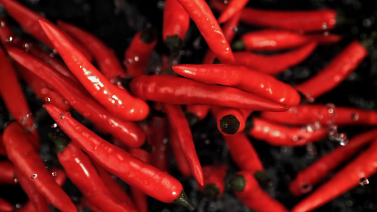 Cabai Merah Segar Terciprat di Air dengan Latar Belakang Hitam.