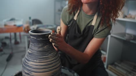 woman shaping a vase on a pottery wheel