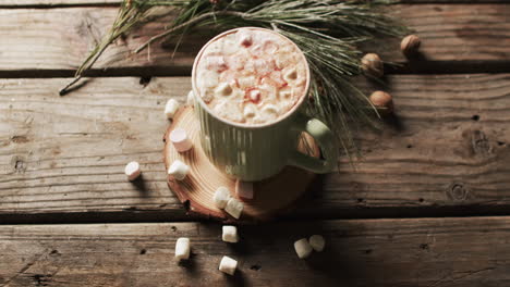 video of mug of chocolate, marshmallows, christmas decorations and copy space on wooden background